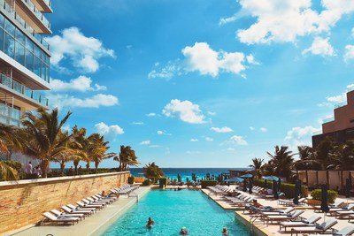 A long pool between rows of sun loungers, leading to the sea.
