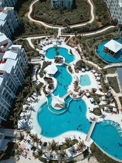 Aerial view of a resort with linked pools, cabanas and palm trees.