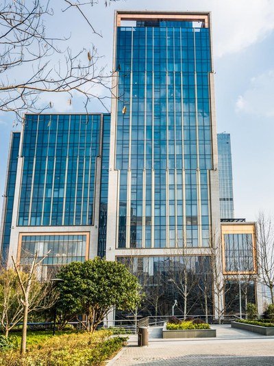 A glass office tower behind a landscaped plaza.