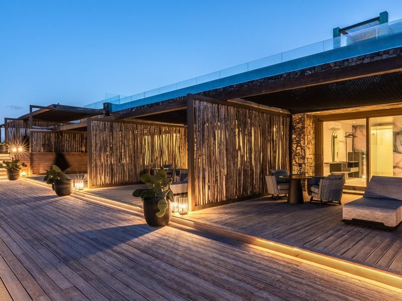 Timber deck walkway at dusk, driftwood privacy screens and warm recessed strip lighting, Mykonos