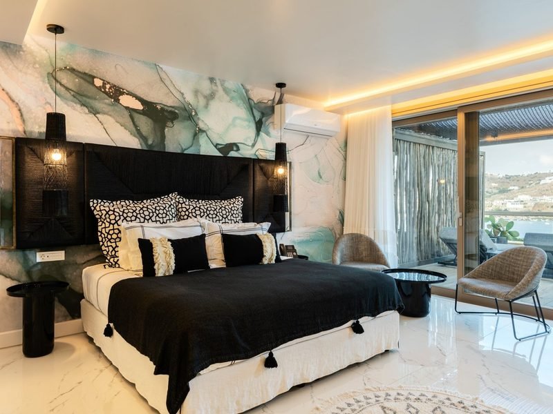 Principal bedroom with black woven headboard, ink-marble mural wall and terrace doors seaward