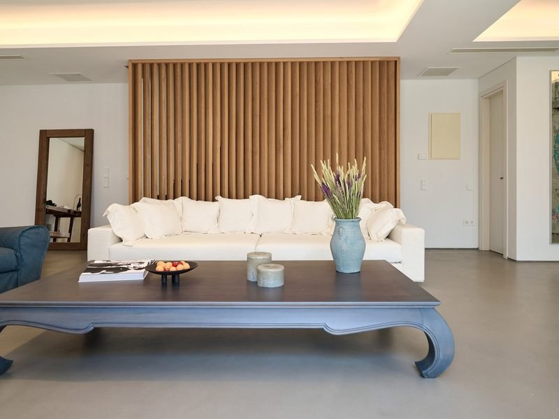 Living room with long linen sofa against a timber slat wall, low lacquered table