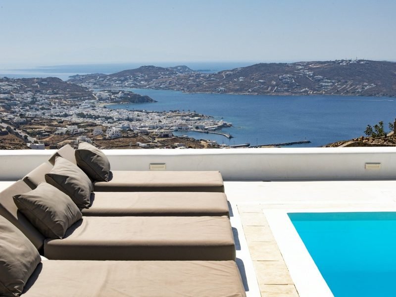 Two day beds with cushions facing the bay, pool edge at right