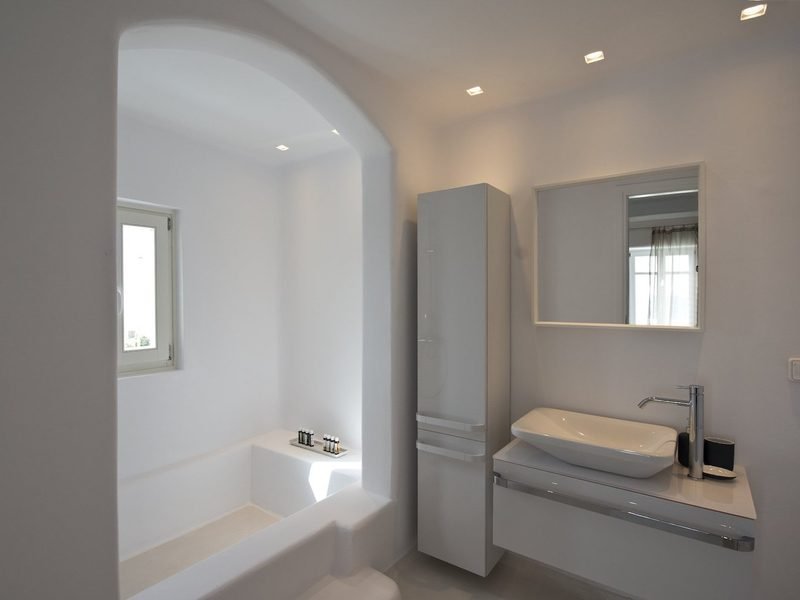 Bathroom vanity with vessel basin and mirror beside an arched, built-in plaster bathtub