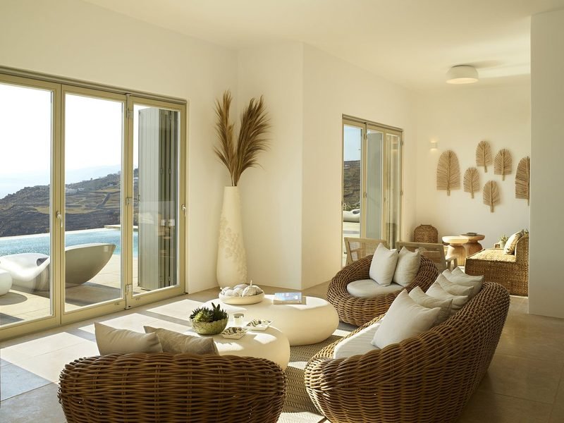 Open-plan living room with woven armchairs, pampas plume vase and doors to the pool