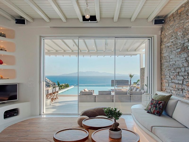 Open-plan living room with sliding glass doors framing the pool and mountains across the water