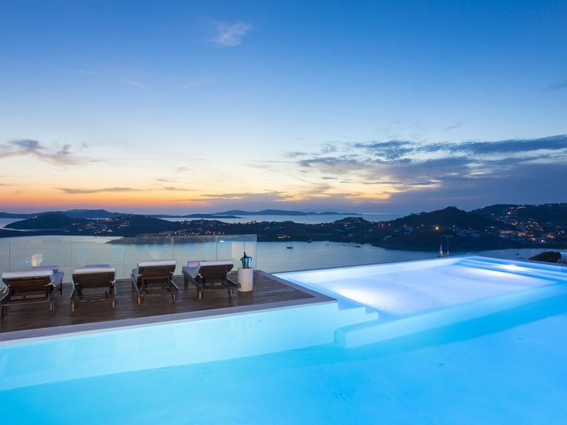 Infinity pool and teak deck loungers facing the sunset over the bay, Agios Lazaros / Ornos