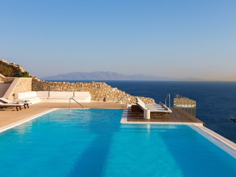 Twin-level pool and sun terrace in daylight, distant mountains across the water, Agios Lazaros / Ornos