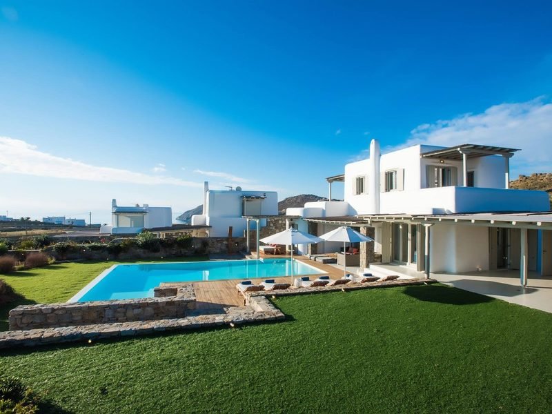 The estate seen from the lawn, white villa above a long pool, Kalafatis / Ano Mera