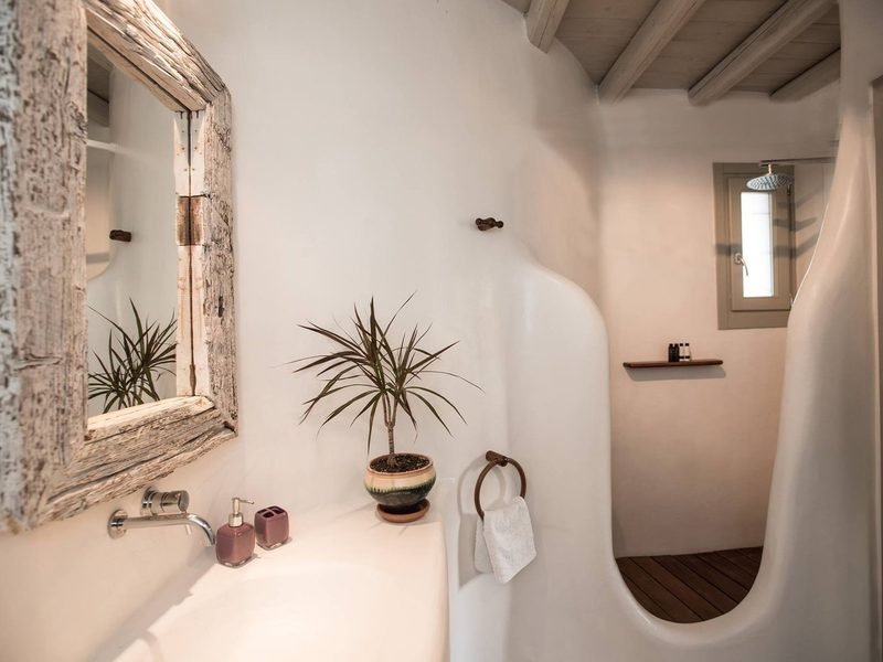Plaster bathroom with driftwood-framed mirror, moulded basin and curved walk-in rain shower