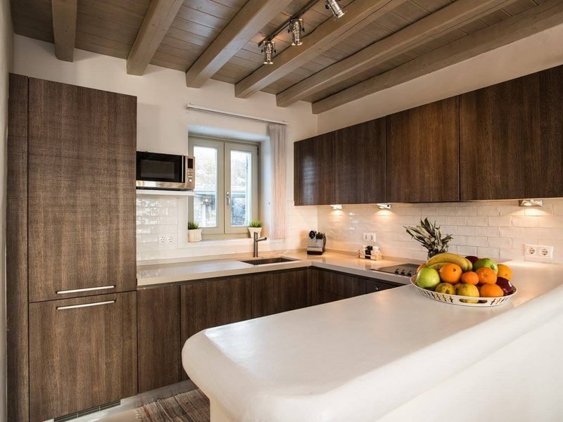 Kitchen in dark timber with white tiled splashback and curved plaster breakfast counter