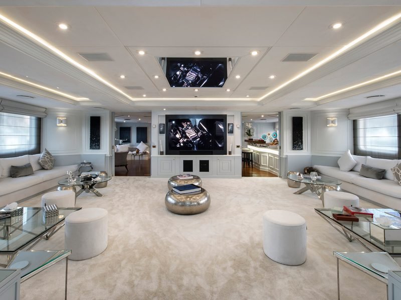 Main saloon with facing white sofas, drop-down cinema screen and pass-through to the bar