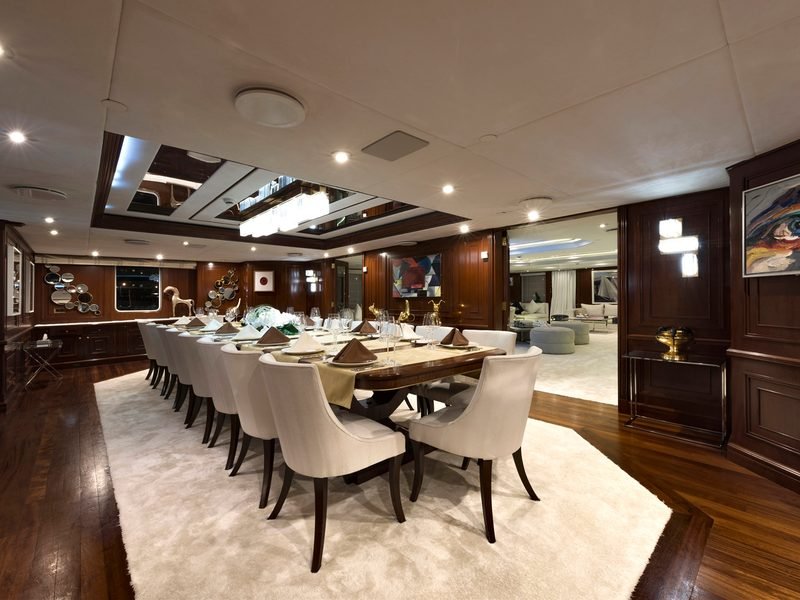 Formal dining saloon set for service, long polished table under a mirrored ceiling panel