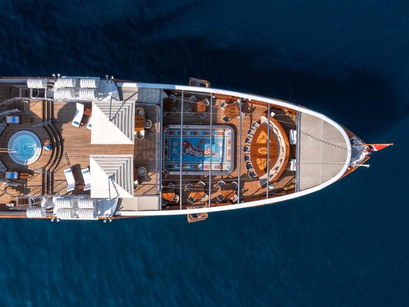 Overhead aerial of the yacht at anchor, mosaic pool and jacuzzi on teak decks