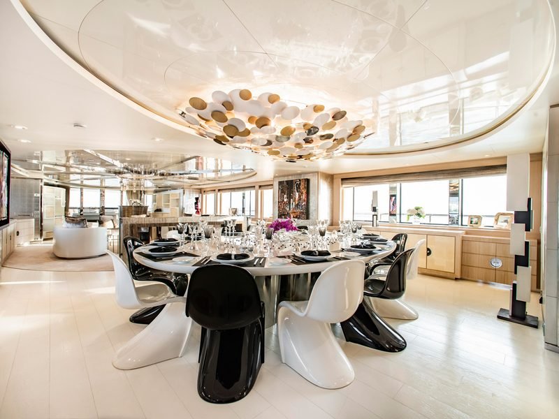 Formal dining room with oval table, black and white chairs, sculptural pebble chandelier
