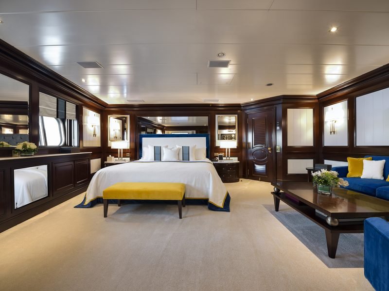 Master suite in dark mahogany joinery with blue and gold bedding and seating area