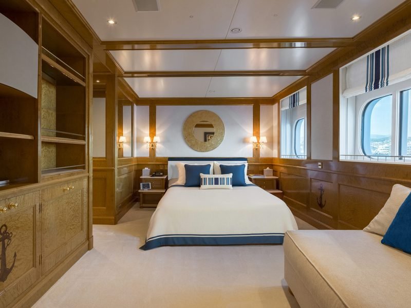 Guest cabin in burr walnut with navy accents and a harbour view through the ports
