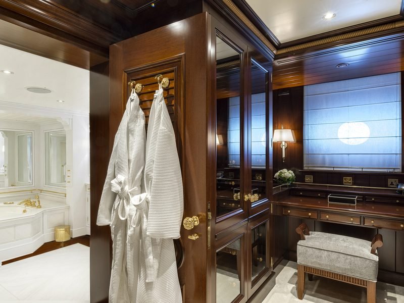 Dressing room with hung robes and brass fittings opening to the marble bathroom