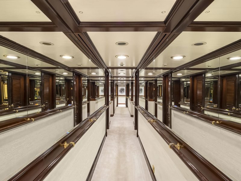 Guest corridor lined with mirrored mahogany bulkheads and polished brass handrails