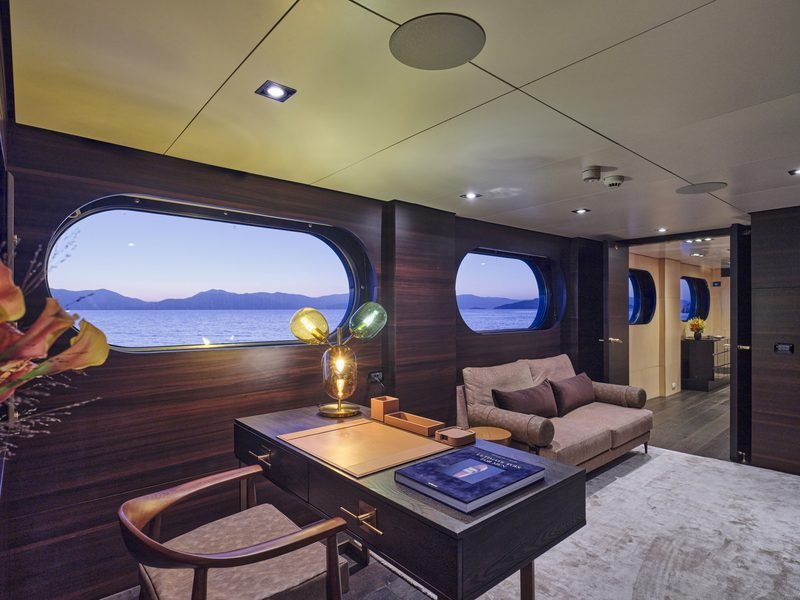 Owner's study at blue hour with macassar joinery, brass desk and oval window