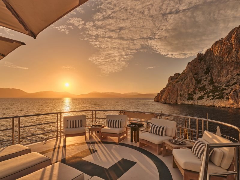 Helipad sundeck at sunset, painted circle marking, teak loungers and open sea