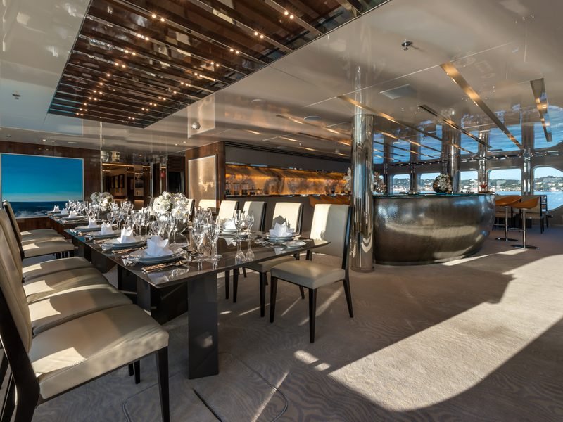 Formal dining room with laid table, hammered-metal curved bar and oval sea windows