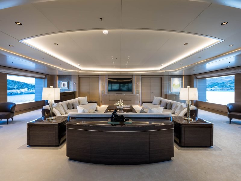 Main saloon with symmetrical cream sofas, cove lighting and sea views both sides