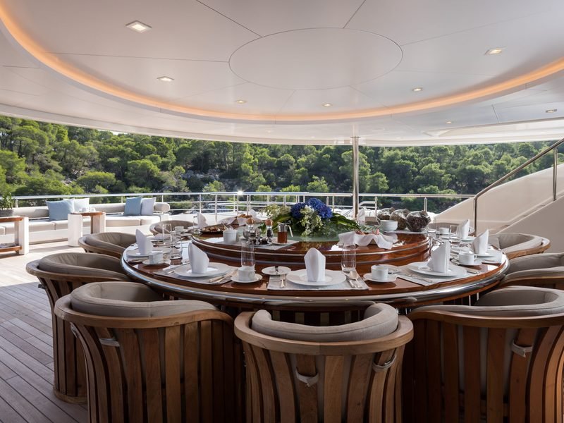 Alfresco dining table set under the curved cove-lit overhang on the aft deck