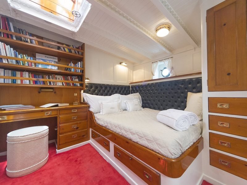 Guest cabin with tufted headboard, campaign chest drawers, bookshelf wall and writing desk