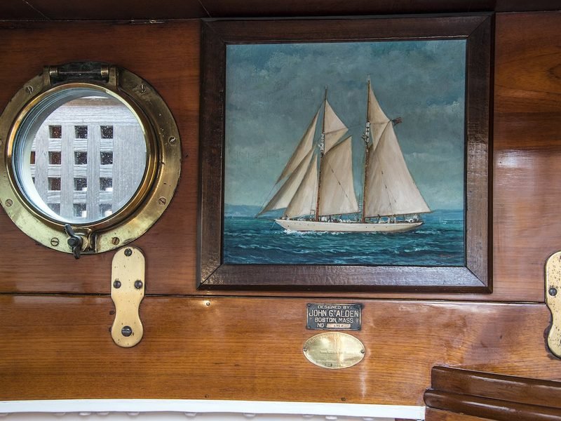 Brass porthole, framed schooner oil and the John G. Alden builder's plate in varnished panelling