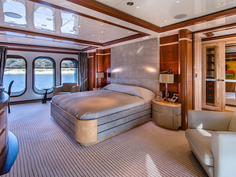 Master stateroom with king berth, suede headboard wall and tall arched sea-view windows