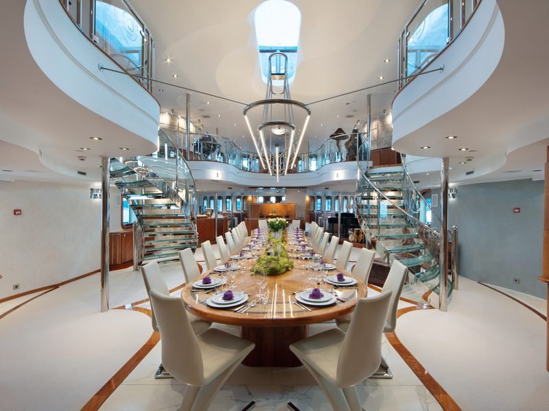 Formal dining atrium with twin glass spiral staircases rising beneath a deck skylight