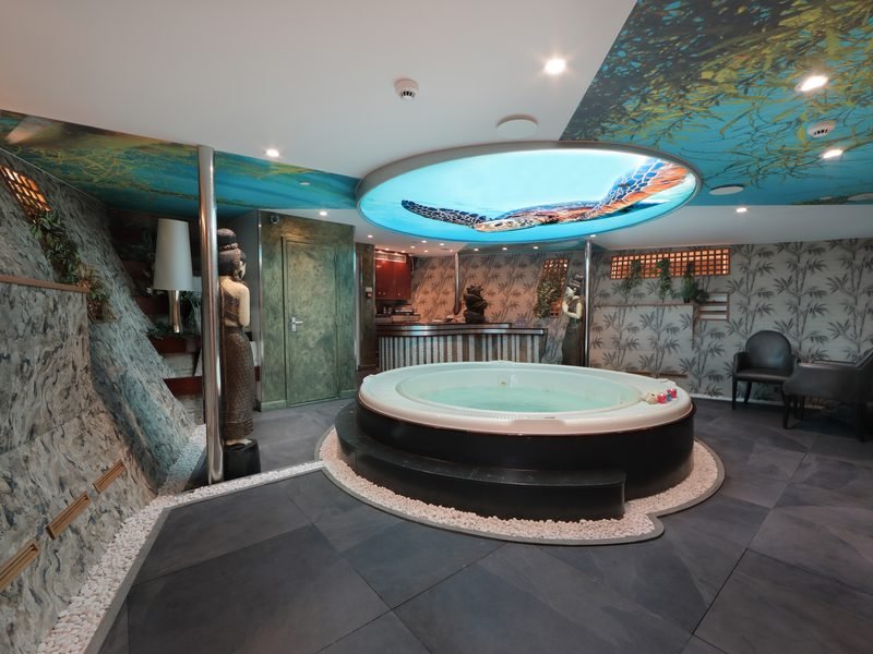 Spa with round jacuzzi, backlit turtle ceiling dome, stone wall and pebble surround