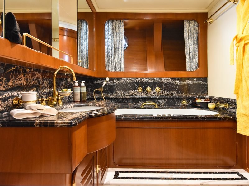 Master bathroom detail: black marble vanity and tub with polished gold fittings